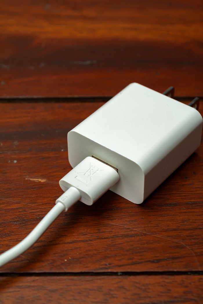 Close-up of a white dual-port charger on a wooden surface, showcasing modern charging technology.