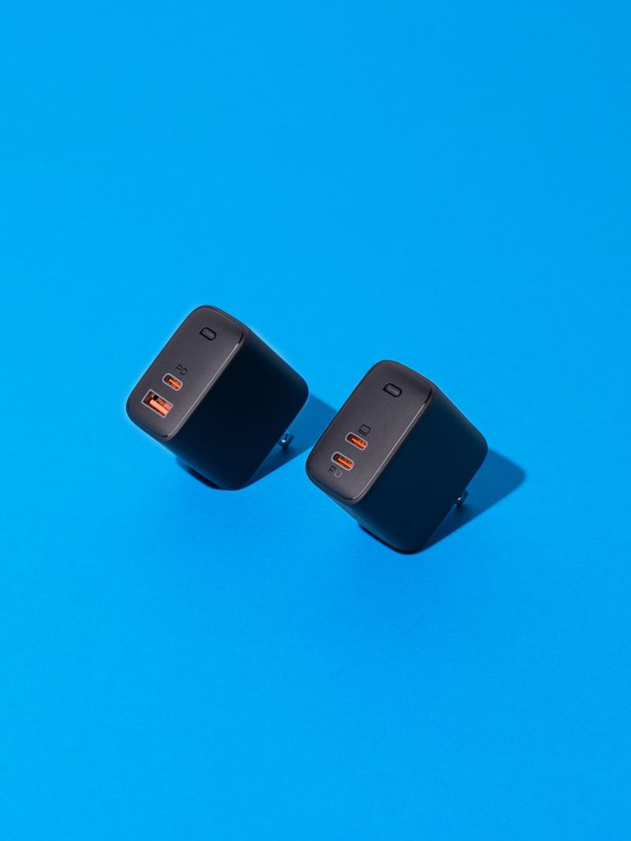 Two black gallium nitride chargers on a vibrant blue background.